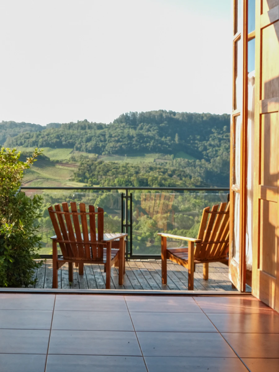 Chairs on a balcony overlooking green hills at sunset