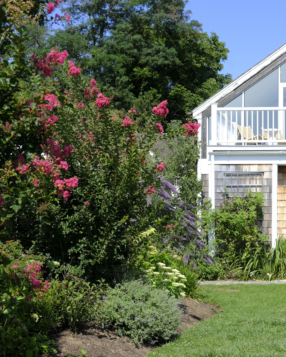 A white farmhouse inn with a porch surrounded by gardens