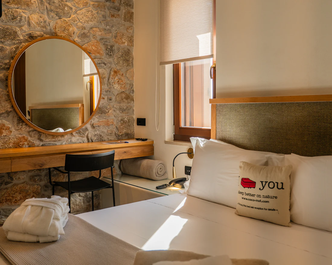 A guest room with a stone wall and round mirror